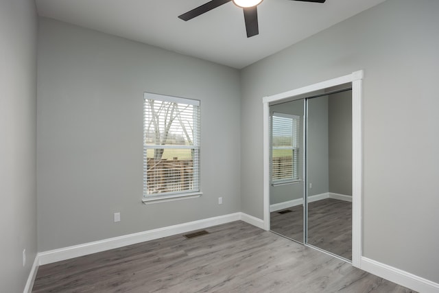 unfurnished bedroom featuring a closet, visible vents, ceiling fan, wood finished floors, and baseboards