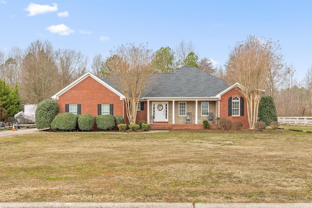 view of front facade with brick siding, fence, and a front lawn