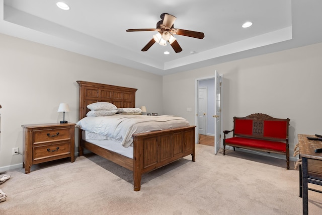 bedroom with baseboards, a tray ceiling, light colored carpet, and recessed lighting