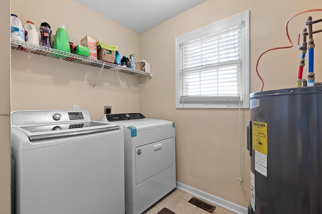 laundry room featuring light tile patterned floors, water heater, separate washer and dryer, laundry area, and baseboards