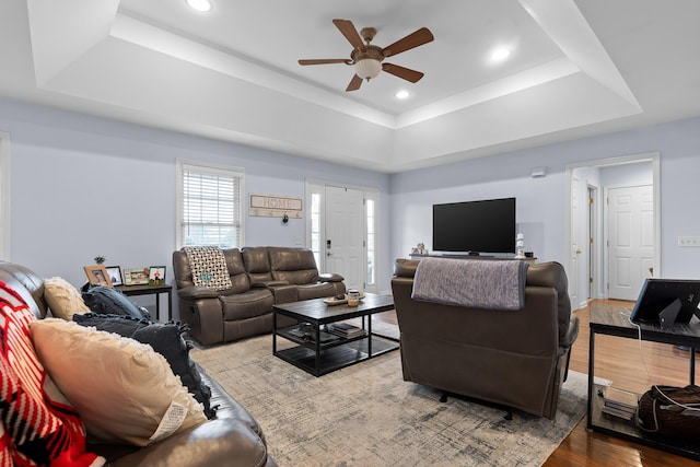 living area featuring ceiling fan, a tray ceiling, wood finished floors, and recessed lighting