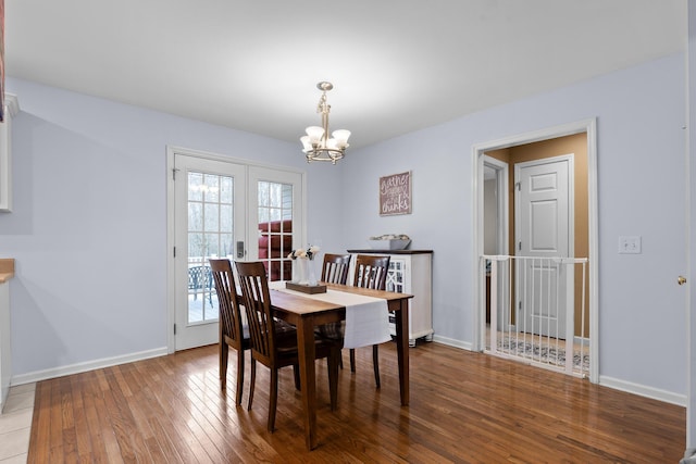 dining area with hardwood / wood-style flooring, baseboards, a chandelier, and french doors