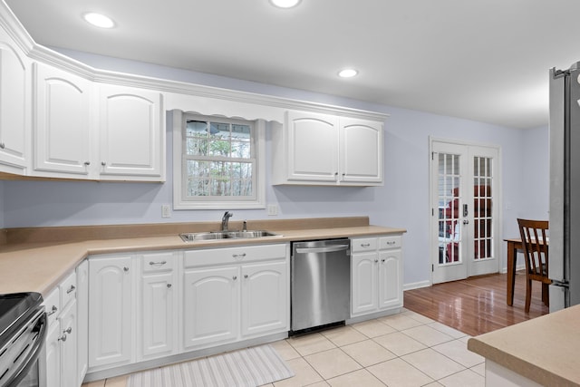 kitchen with french doors, light tile patterned floors, appliances with stainless steel finishes, white cabinets, and a sink