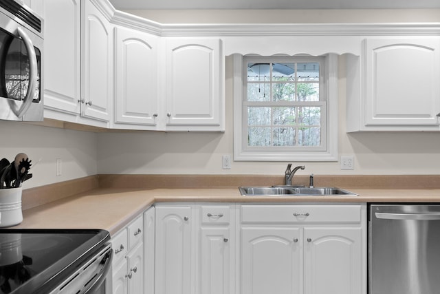 kitchen with white cabinets, stainless steel appliances, a sink, and light countertops