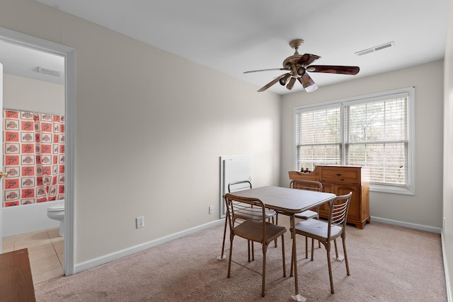 dining room with visible vents, ceiling fan, light carpet, and baseboards