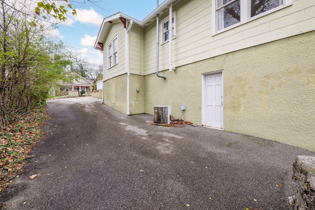 view of home's exterior with aphalt driveway, central AC, and stucco siding