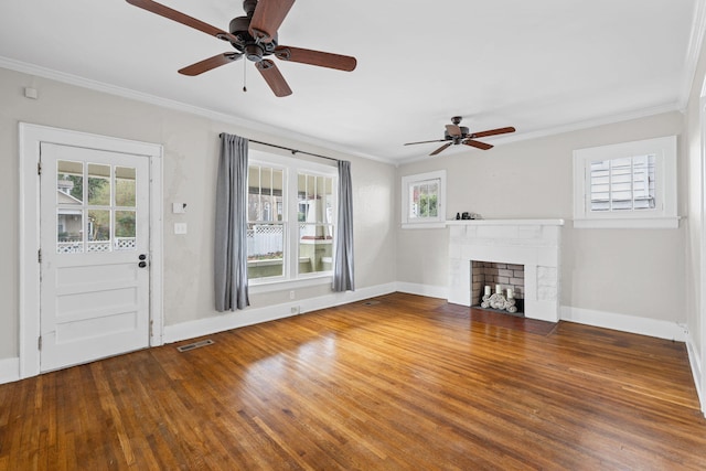 unfurnished living room with a brick fireplace, visible vents, crown molding, and wood finished floors