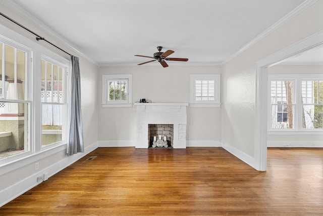 unfurnished living room featuring wood finished floors, ornamental molding, a fireplace with flush hearth, and a wealth of natural light