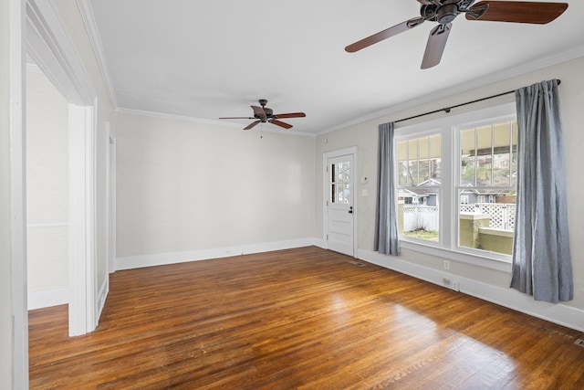 empty room with baseboards, crown molding, and wood finished floors