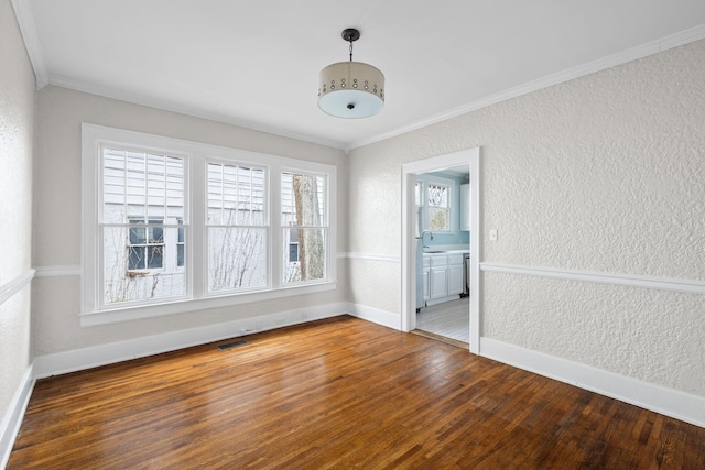 spare room featuring a textured wall, hardwood / wood-style floors, a sink, and visible vents