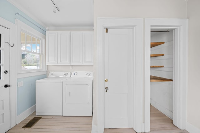 laundry room with baseboards, washing machine and clothes dryer, cabinet space, and light wood-style floors