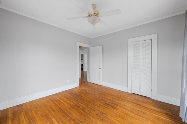 unfurnished bedroom with wood-type flooring, crown molding, and baseboards