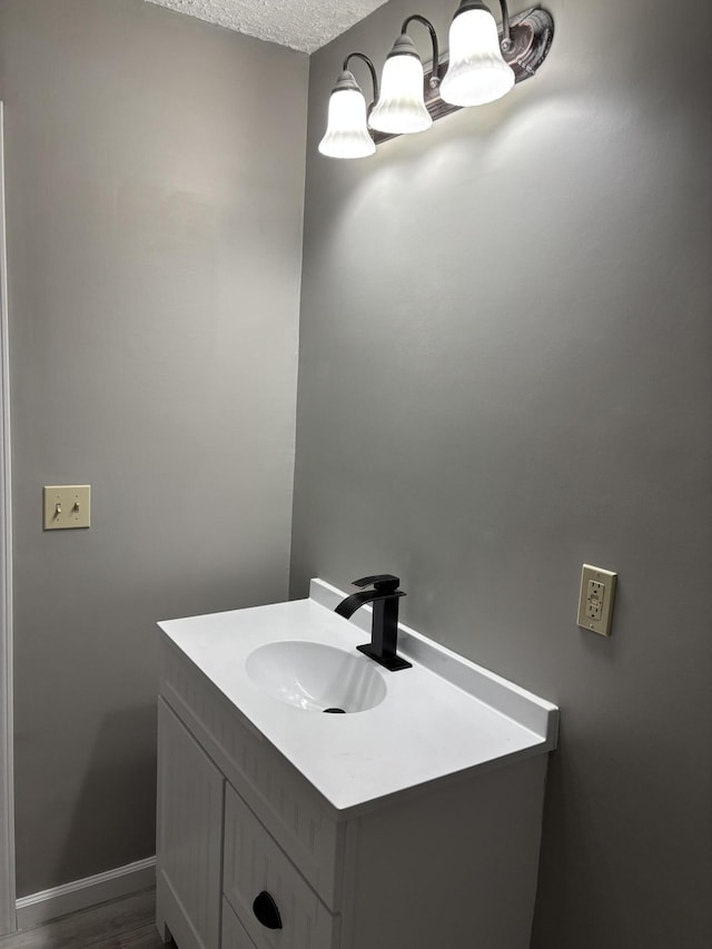 bathroom with baseboards, a textured ceiling, and vanity