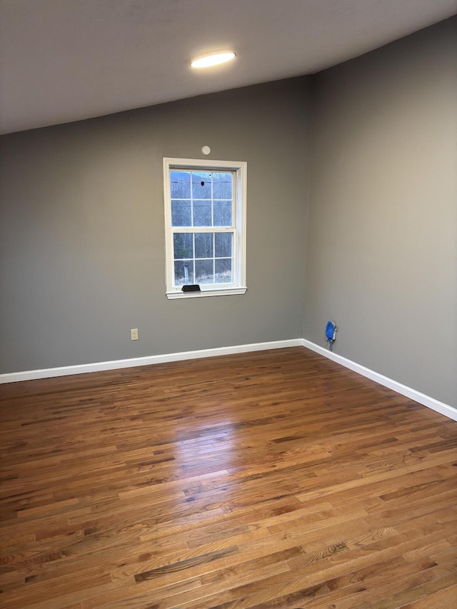 unfurnished room with lofted ceiling, wood finished floors, and baseboards