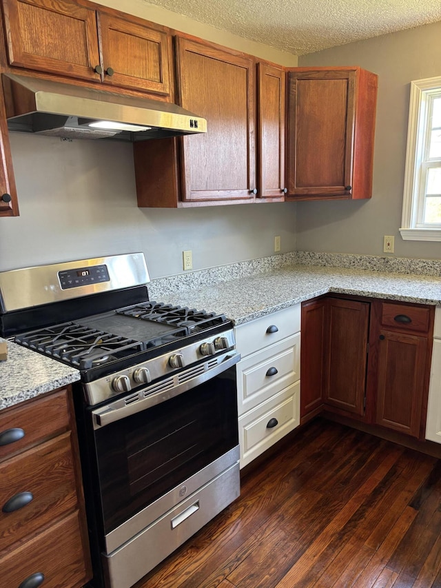 kitchen featuring ventilation hood, brown cabinetry, stainless steel range with gas cooktop, dark wood-style floors, and a textured ceiling