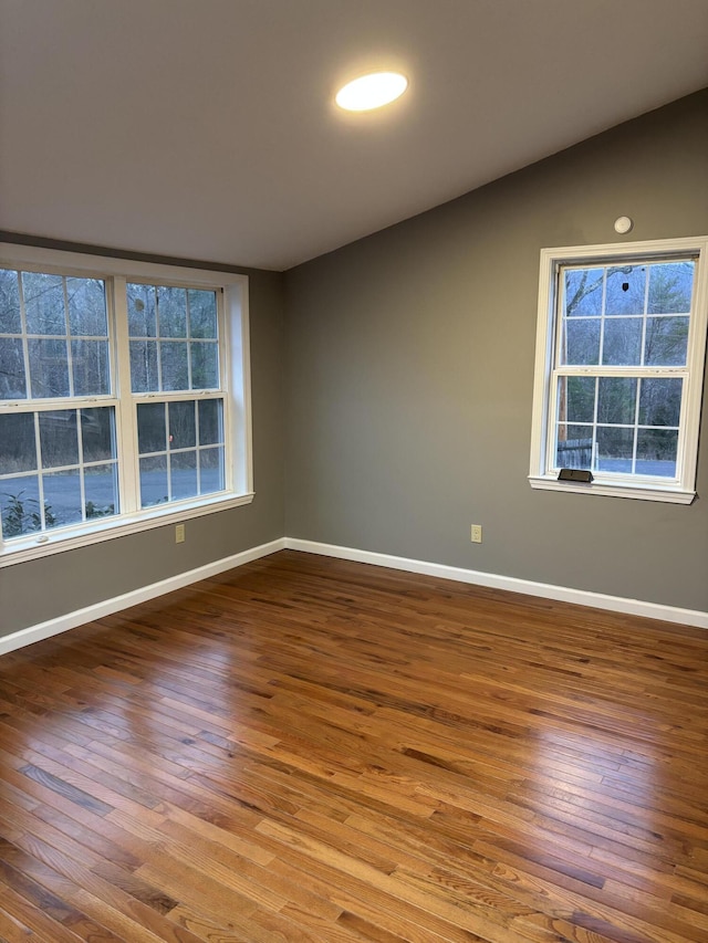 unfurnished room featuring baseboards, lofted ceiling, and wood finished floors