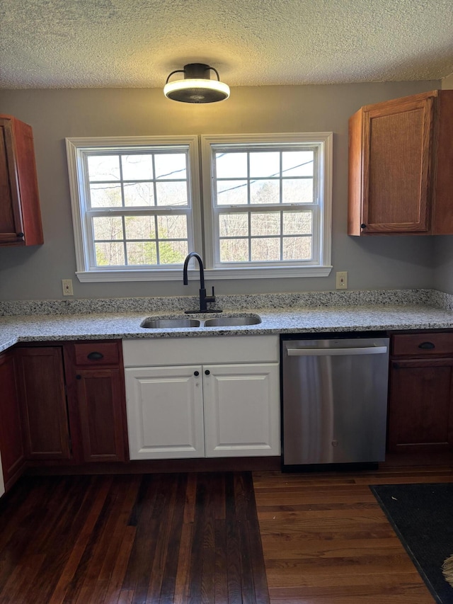 kitchen with stainless steel dishwasher, a textured ceiling, dark wood-style flooring, and a sink