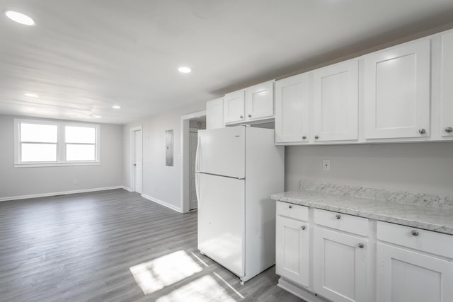 kitchen with light wood-type flooring, freestanding refrigerator, recessed lighting, white cabinets, and baseboards