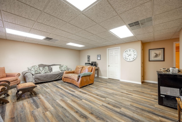 living area with visible vents, a drop ceiling, baseboards, and wood finished floors