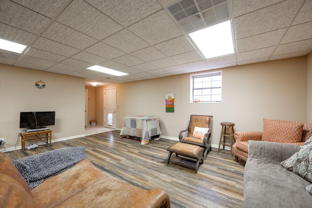 living room featuring a paneled ceiling, baseboards, visible vents, and wood finished floors