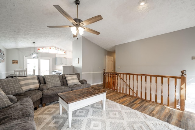 living room with a ceiling fan, vaulted ceiling, a textured ceiling, and wood finished floors