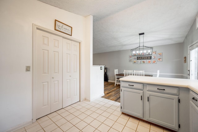 kitchen featuring a peninsula, light tile patterned floors, light countertops, and a textured ceiling