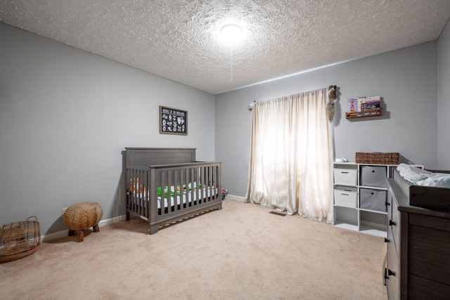 carpeted bedroom featuring a nursery area, a textured ceiling, and baseboards