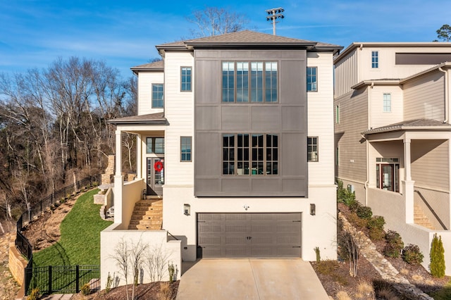 view of front of home featuring stucco siding, fence, concrete driveway, a garage, and stairs