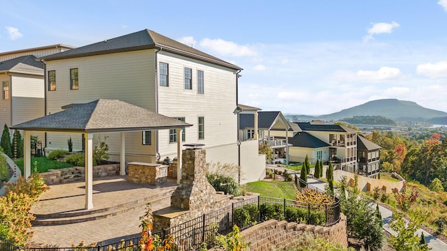 back of property with area for grilling, a patio, fence, a mountain view, and a shingled roof