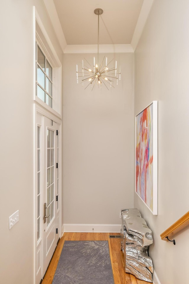 interior space featuring a notable chandelier, ornamental molding, baseboards, and wood finished floors