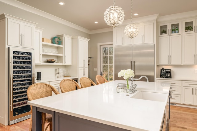 kitchen featuring stainless steel built in fridge, a breakfast bar, beverage cooler, ornamental molding, and a sink