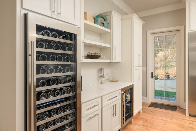 bar with wine cooler, stainless steel fridge, a bar, and light wood-type flooring