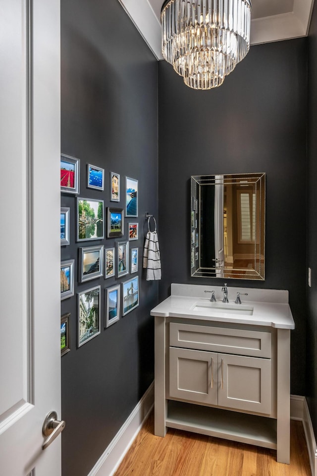 bathroom featuring baseboards, an inviting chandelier, wood finished floors, and vanity