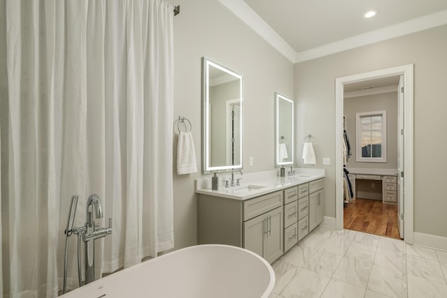 bathroom featuring a sink, a soaking tub, marble finish floor, and crown molding