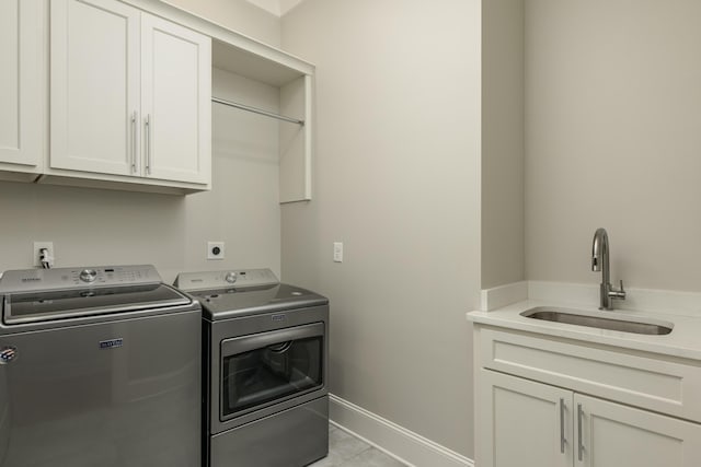 laundry area featuring washer and clothes dryer, a sink, cabinet space, light tile patterned floors, and baseboards