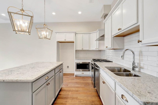 kitchen with gray cabinets, light wood-style flooring, decorative backsplash, appliances with stainless steel finishes, and a sink