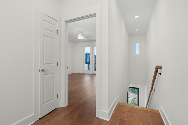 corridor with recessed lighting, baseboards, wood finished floors, and an upstairs landing