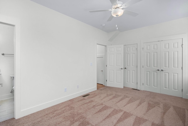 unfurnished bedroom featuring baseboards, carpet, visible vents, and multiple closets