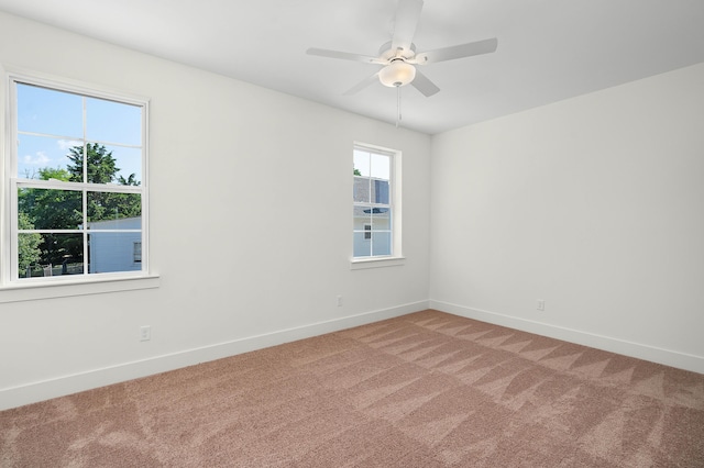 empty room featuring light carpet, a ceiling fan, and baseboards