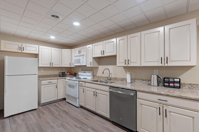 kitchen featuring white appliances, a sink, visible vents, white cabinetry, and light wood-type flooring