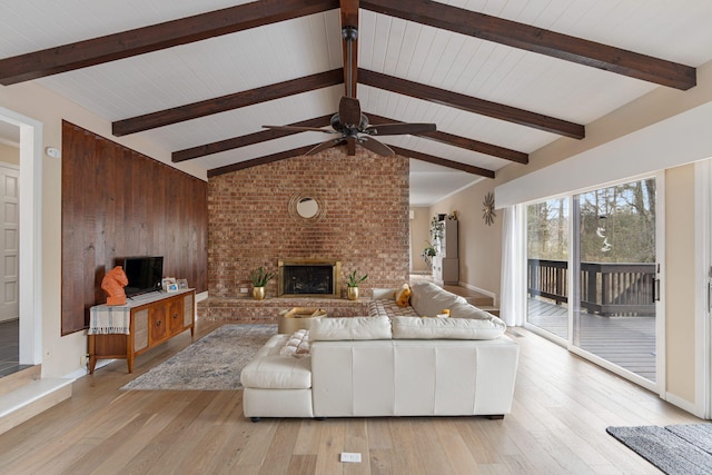 living room featuring vaulted ceiling with beams, light wood-style floors, and a fireplace