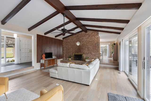 living room with a fireplace, light wood-style flooring, and lofted ceiling with beams