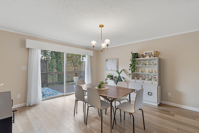 dining room featuring baseboards, ornamental molding, a textured ceiling, light wood-type flooring, and a notable chandelier