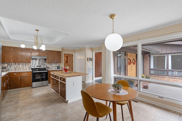 kitchen with under cabinet range hood, wooden counters, stainless steel electric stove, tasteful backsplash, and a raised ceiling