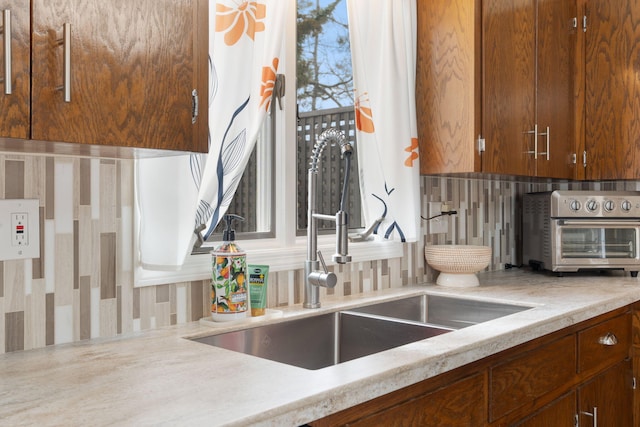 kitchen with light countertops, a toaster, a sink, and backsplash