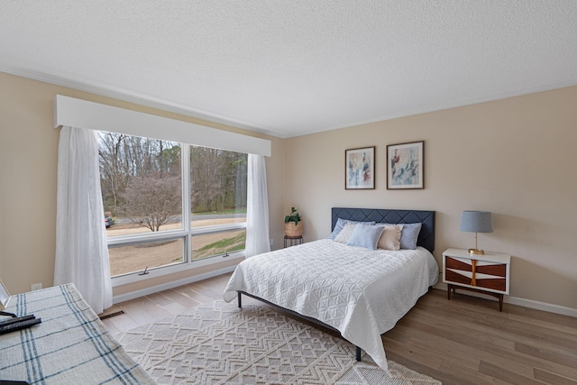 bedroom with light wood-style flooring, baseboards, and a textured ceiling