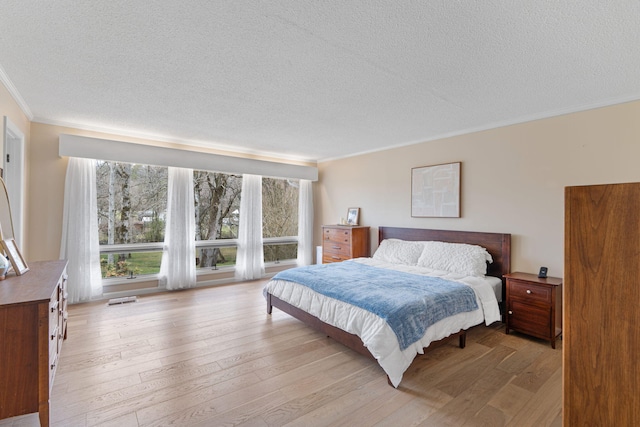 bedroom featuring light wood-type flooring, visible vents, and crown molding