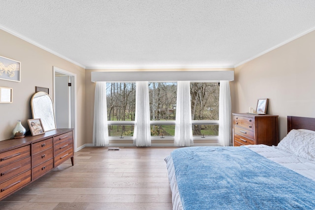 bedroom with a textured ceiling, light wood finished floors, and crown molding