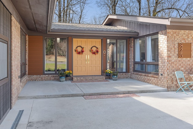 doorway to property with board and batten siding and brick siding