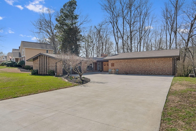 mid-century modern home featuring driveway, brick siding, and a front yard